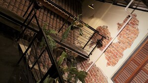 Una escalera con barandillas metálicas, un muro de ladrillo con diseño de estampilla y una puerta de madera.