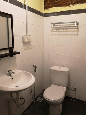 Un baño pequeño y limpio con un lavamanos blanco, un inodoro y un perchero para toallas.