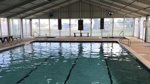 An indoor swimming pool with clear water, marked lanes, and benches along the sides. - Beach house on private resort (Port Isabel)