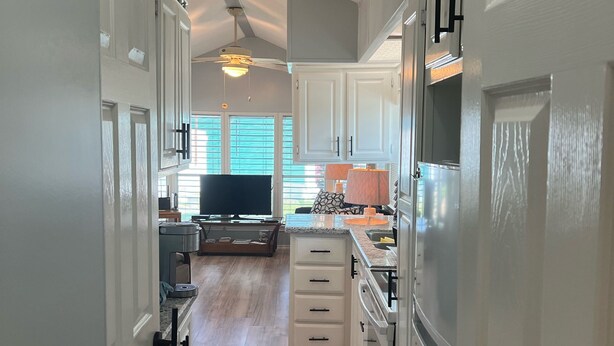 A modern kitchen with white cabinetry, a central island, and a ceiling fan. - Beach house on private resort (Port Isabel)
