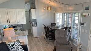 A modern kitchen with white cabinets, a granite countertop, and a dining area with a table and chairs. - Beach house on private resort (Port Isabel)