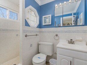 A bathroom with a white toilet, a sink with a mirror, and a shower area.