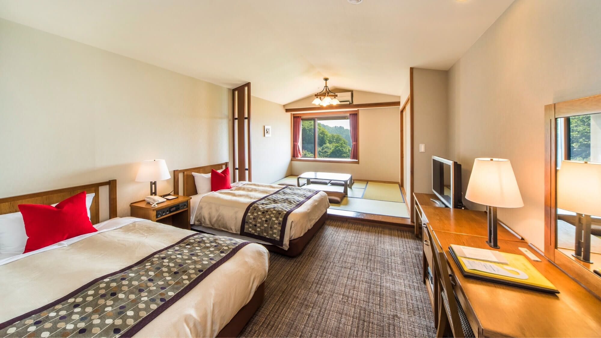 Ett hotellrum med två sängar, ett skrivbord med en tv, ett fönster med utsikt och en taklampa.