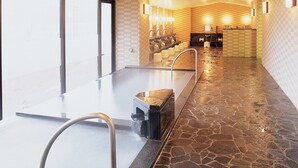Un espace spa doté d’un sol en pierre, d’un long banc et d’un lavabo avec un robinet.