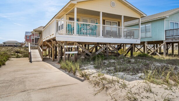 A beachfront house with a balcony, wooden deck, and a sandy path leading to the entrance. - Cute beach house w/ramp for easy access. 3Bd/2Ba- Great Gulf Views/easy access. (Gulf Shores)