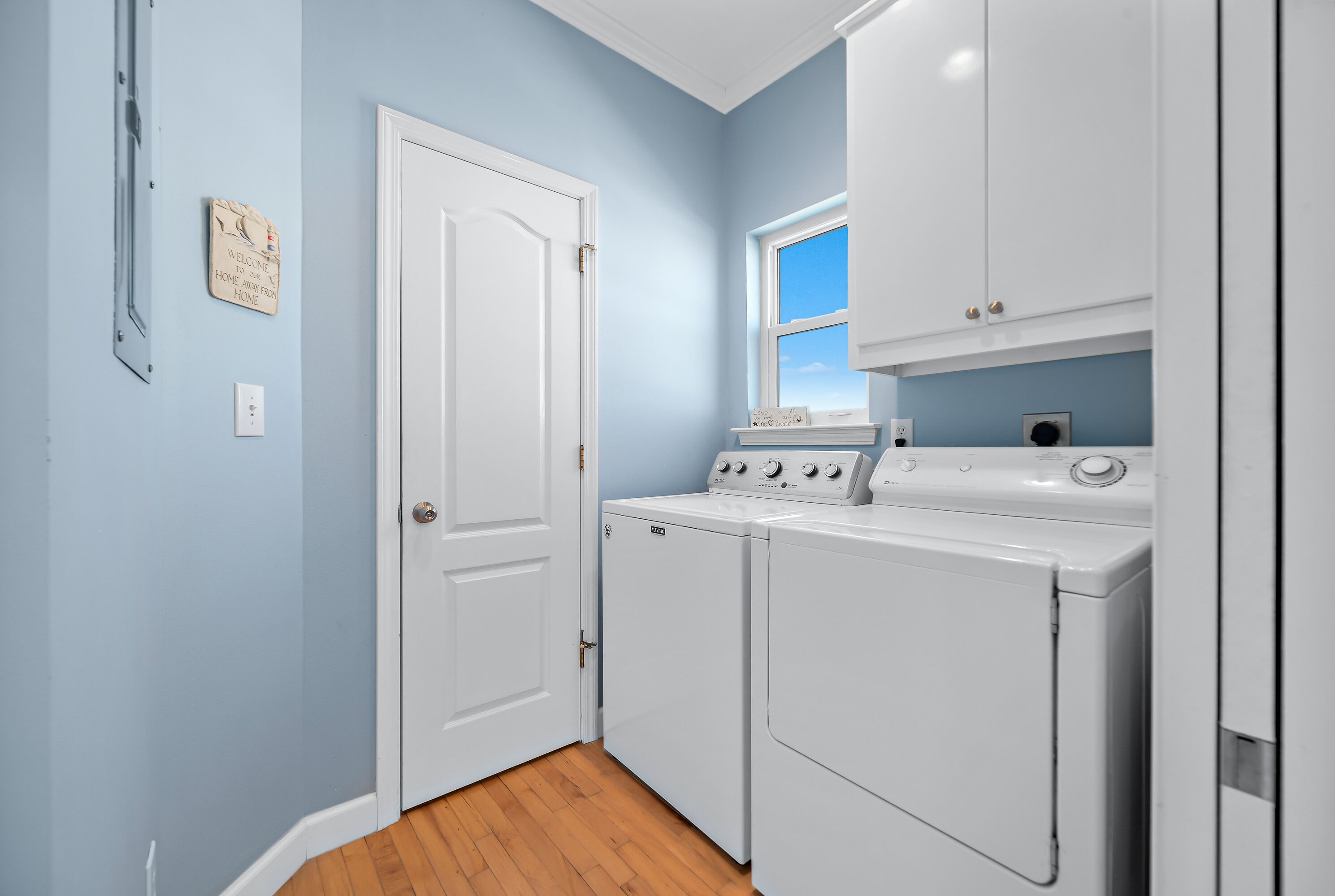 A laundry room with a white door, a window, and a wall-mounted sign.