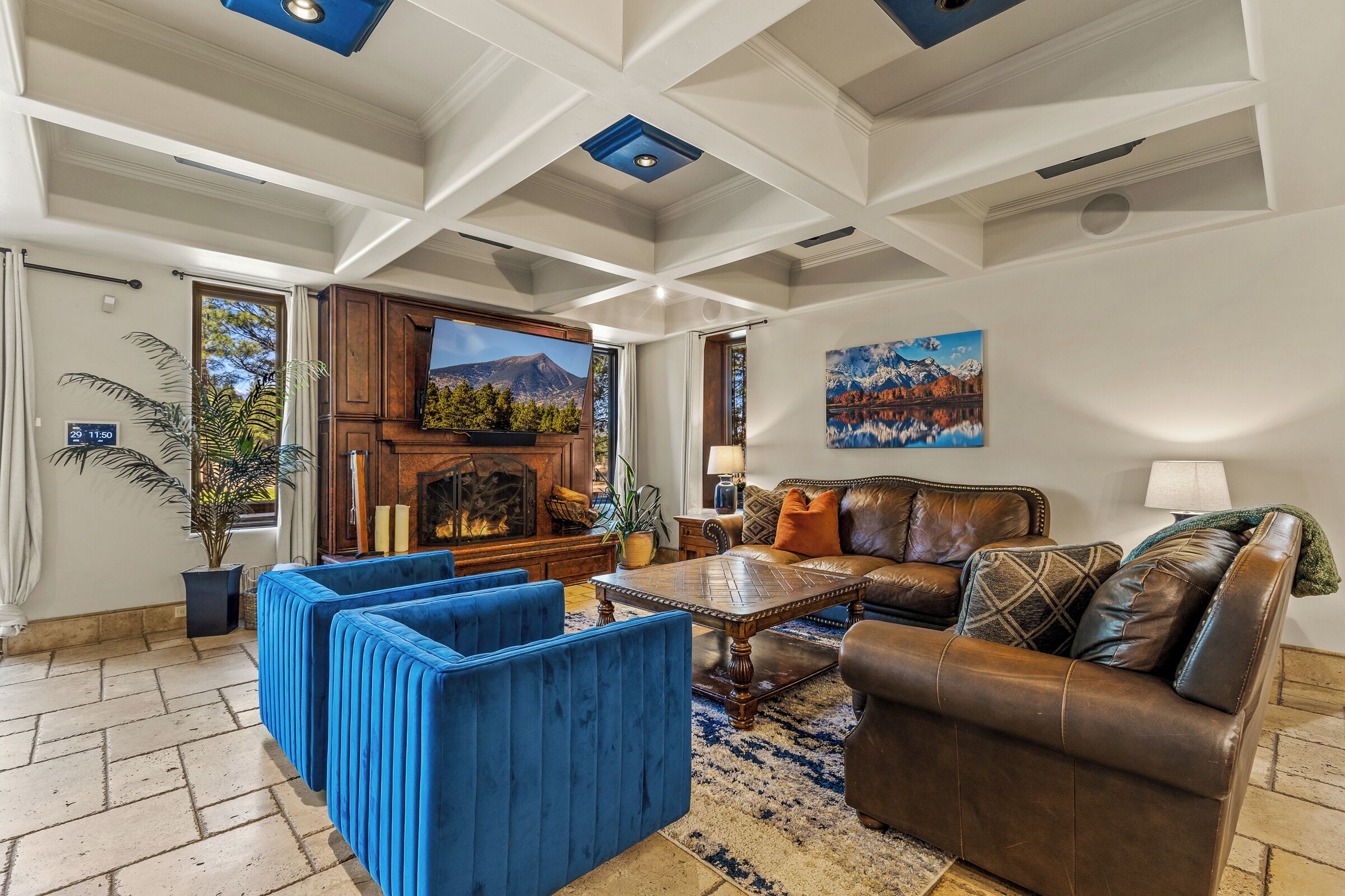 A living room with a fireplace, blue sofas, a brown leather sofa, and a painting on the wall.