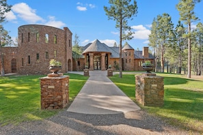 A stone building with a central courtyard, a gazebo, and a pathway leading to the entrance.
