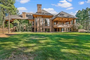 A large stone building with multiple levels, large windows, and a spacious lawn. - The Castle – Luxury Northern Arizona Estate | Sleeps 17 (Flagstaff)
