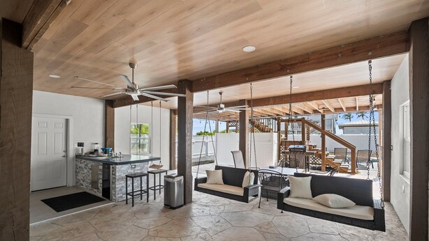 A spacious living area with a stone floor, a kitchen with a bar, and a swing chair.