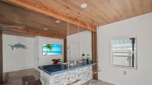 A kitchen with a stone countertop, wooden ceiling beams, a television, and a window.