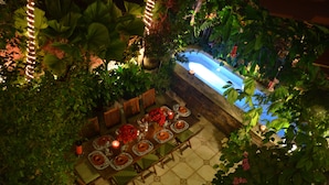 An outdoor dining area with a pool, surrounded by lush greenery and potted plants. - Ocean View - In the Heart of Old Town -Casa Romance Escondido (Puerto Vallarta)