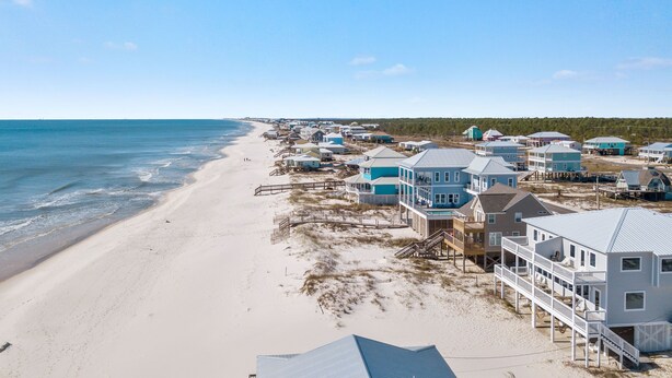 A beachfront property with multiple houses, a sandy beach, and a clear blue sky. - East Side of Updated, Gorgeous 4 BR Gulf Front Duplex. (Gulf Shores)