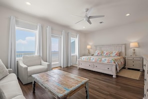 A bedroom with a bed, a chair, a table, and a nightstand.