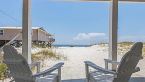 Two white Adirondack chairs facing a sandy beach with a house in the background. - East Side of Updated, Gorgeous 4 BR Gulf Front Duplex. (Gulf Shores)
