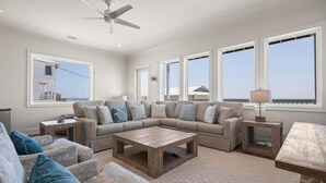 A spacious living room with a sectional sofa, a wooden coffee table, and a ceiling fan. - East Side of Updated, Gorgeous 4 BR Gulf Front Duplex. (Gulf Shores)
