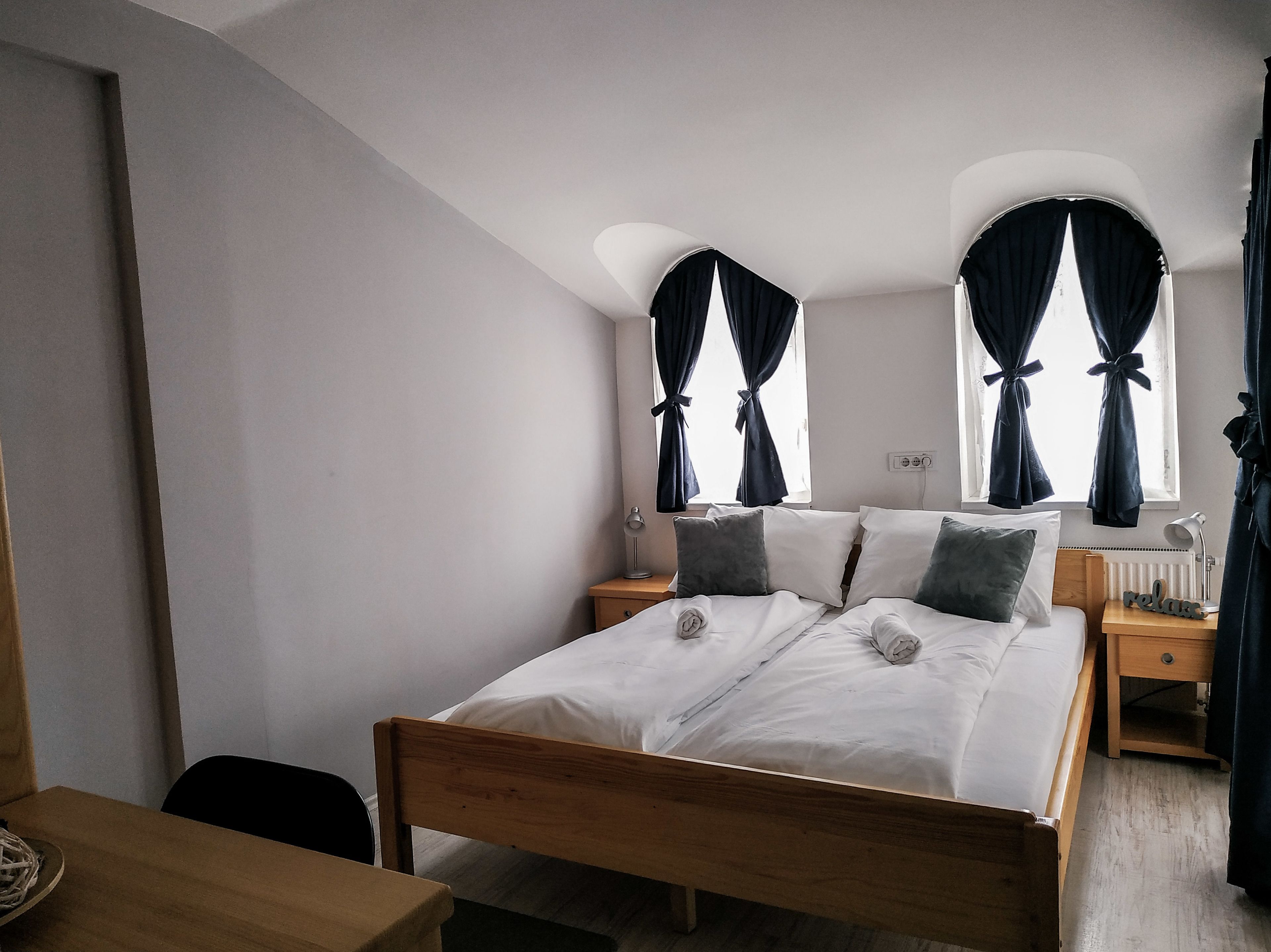 Un dormitorio con una cama de madera, dos mesitas de noche, un buró y una silla.