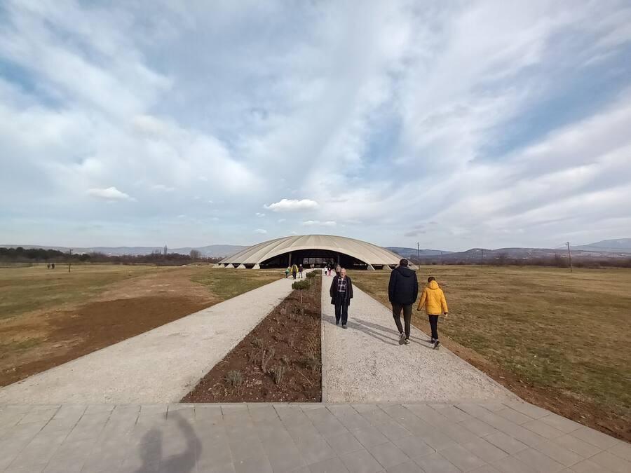 Un camino que lleva a una construcción grande, moderna y con forma de cúpula en un campo abierto.