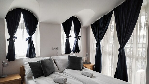 A neatly made bed with a pillow, a bedside lamp, and a nightstand. -  Bloom Inn (Niš)