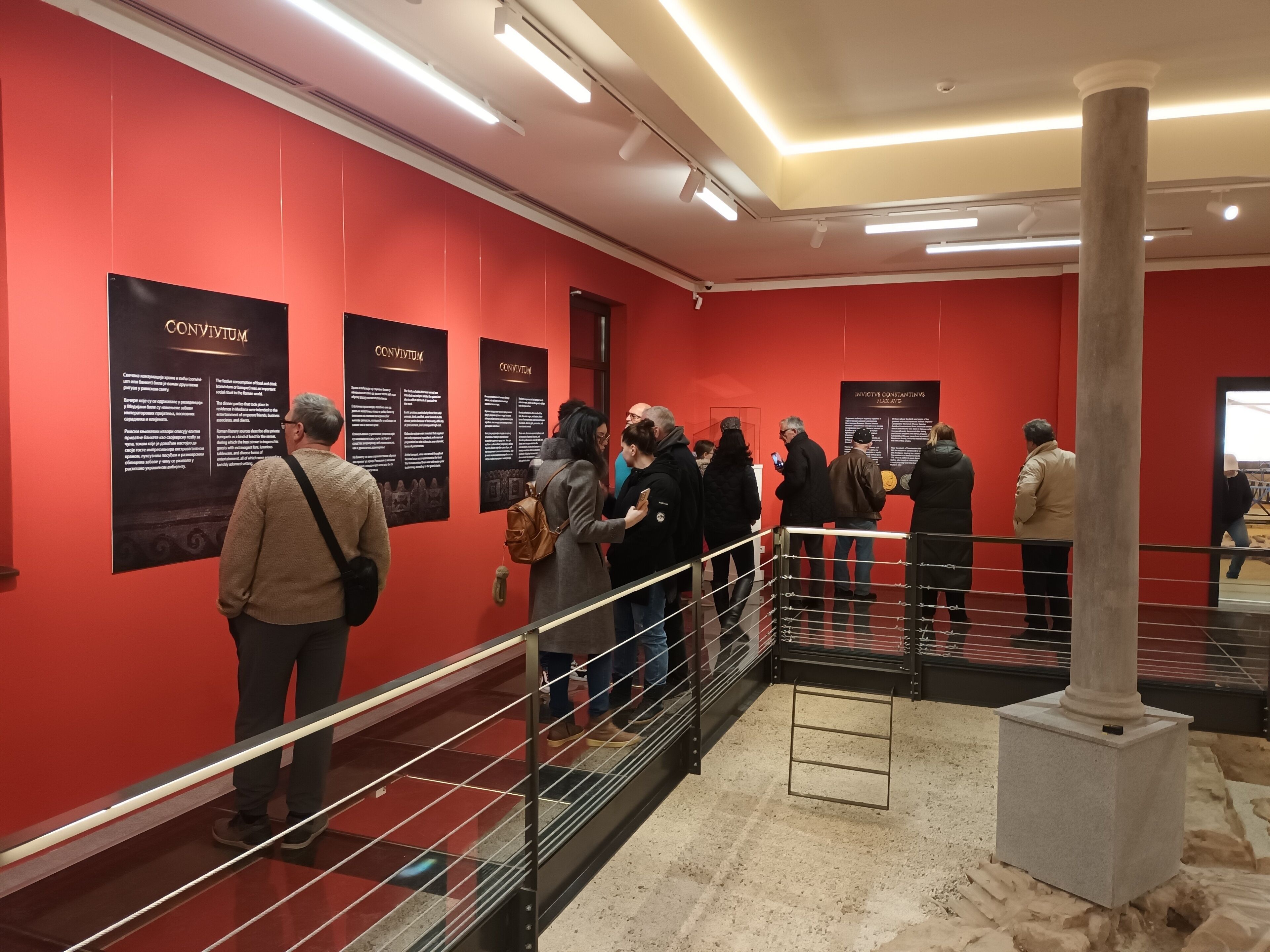 A red-walled hallway with informational posters and a metal railing.