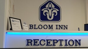 A reception desk with a logo, name, and a list of services including information, tourist maps, and money exchange. -  Bloom Inn (Niš)