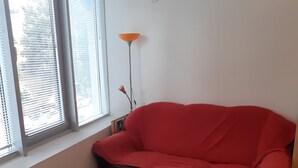 A room with a red sofa, a white table, and a floor lamp. -  Bloom Inn (Niš)