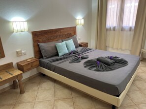 A neatly made bed with pillows, a wooden headboard, bedside tables, and wall-mounted lights.