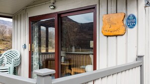 Une terrasse en bois avec une porte vitrée donnant sur une pièce, une enseigne indiquant « Lapwing », et un panneau indiquant qu’il s’agit d’un hébergement touristique écossais proposant des services de restauration.