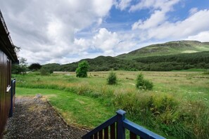 A rural landscape with a wooden building and a grassy field.