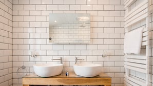 Une salle de bain avec deux lavabos blancs, un meuble-lavabo en bois et un miroir au-dessus des lavabos.