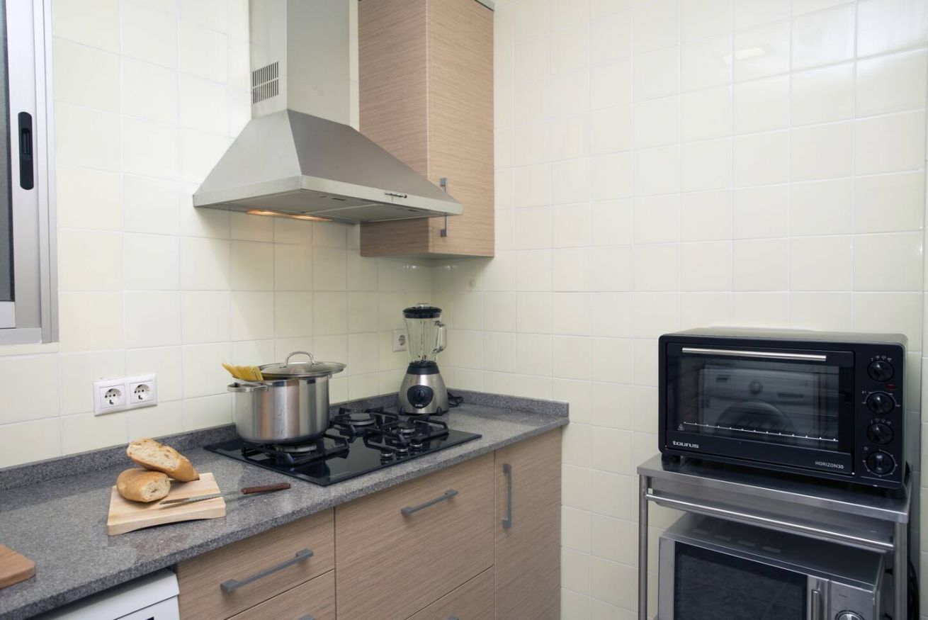 Una cocina con estufa a gas, licuadora, horno tostador y una olla sobre la encimera.