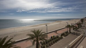 A beach with a paved walkway, palm trees, and a distant pier. - Singular Stays El Faro (Puçol)