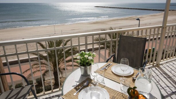 A balcony with a table set for two, overlooking a beach. - Singular Stays El Faro (Puçol)