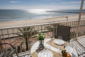 Een balkon met een tafel gedekt voor twee, met uitzicht op een strand.