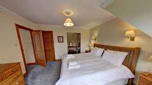 Une chambre à coucher avec un grand lit, une tête de lit en bois, des lampes de chevet et un miroir.