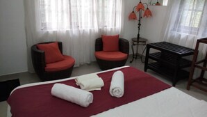 A hotel room with a bed, two armchairs, a small table, and a lamp. - Enrich Bungalow (Kandy)