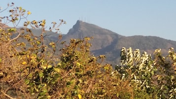 A mountainous landscape with sparse vegetation in the foreground and a clear sky.
