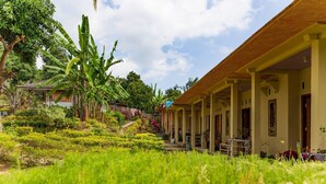 Un bâtiment doté d’un espace extérieur abrité, entouré d’une végétation luxuriante et de bananiers.