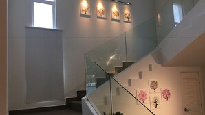 A modern staircase with glass railings, a white door, and wall-mounted artwork. - Lux Desaru Villa (Bandar Penawar)