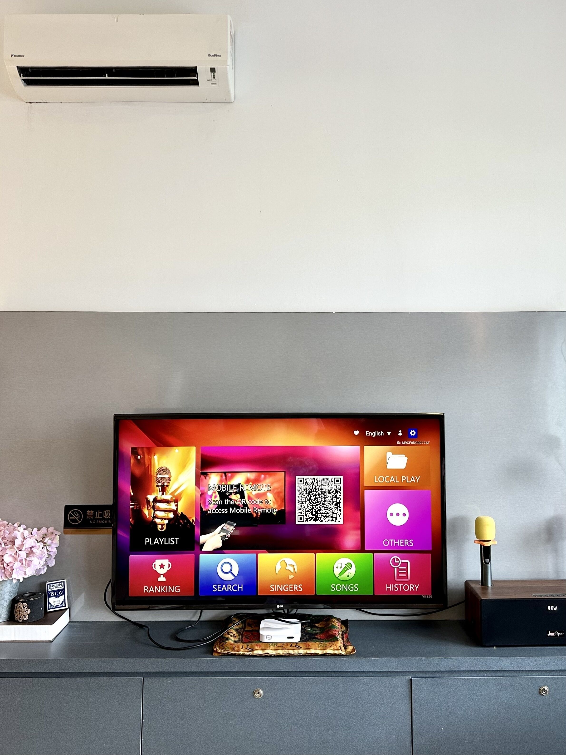 A television mounted on a wall with a remote control and a decorative item beside it.