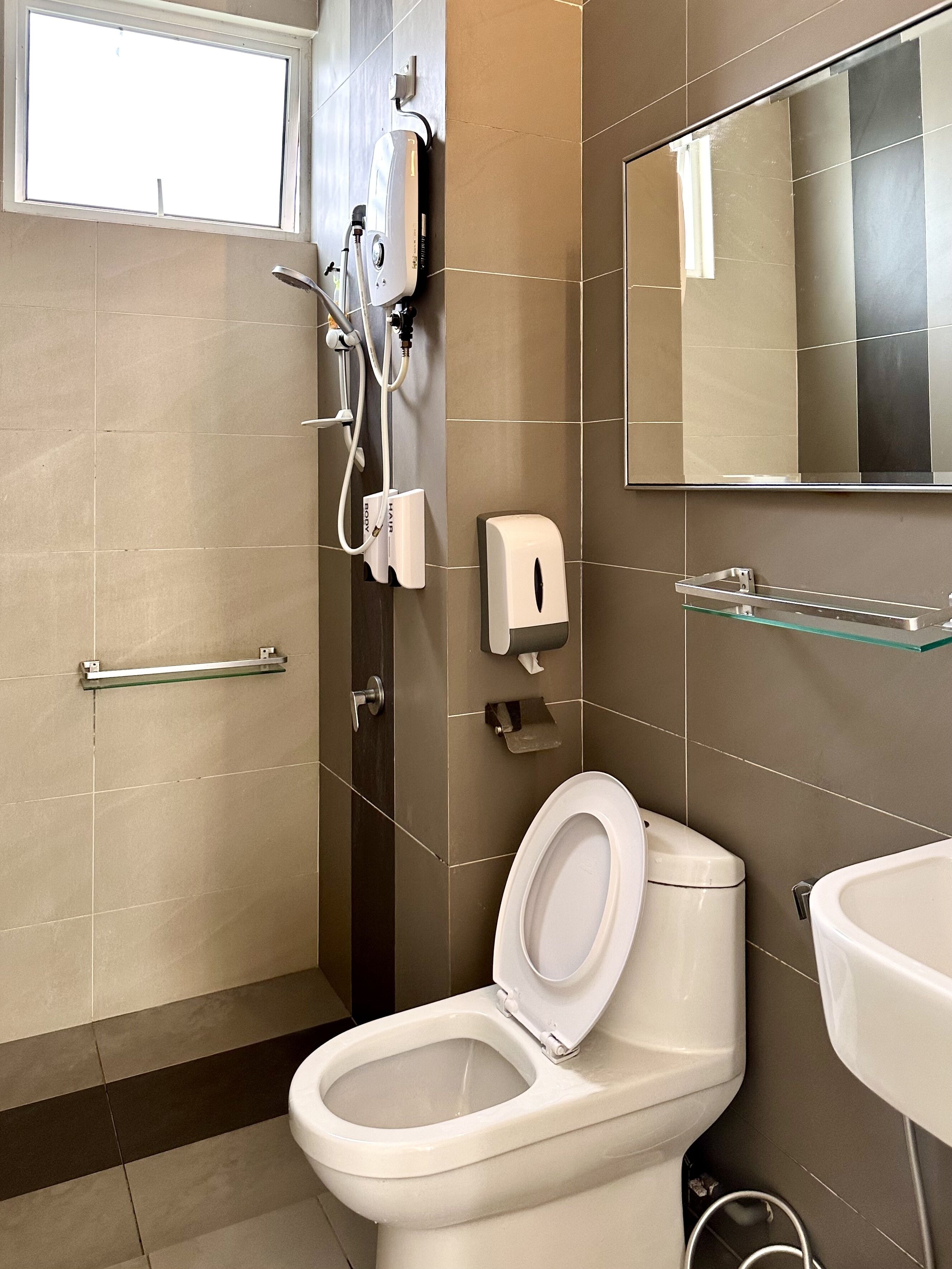A modern bathroom with a toilet, bidet, and a glass shelf.