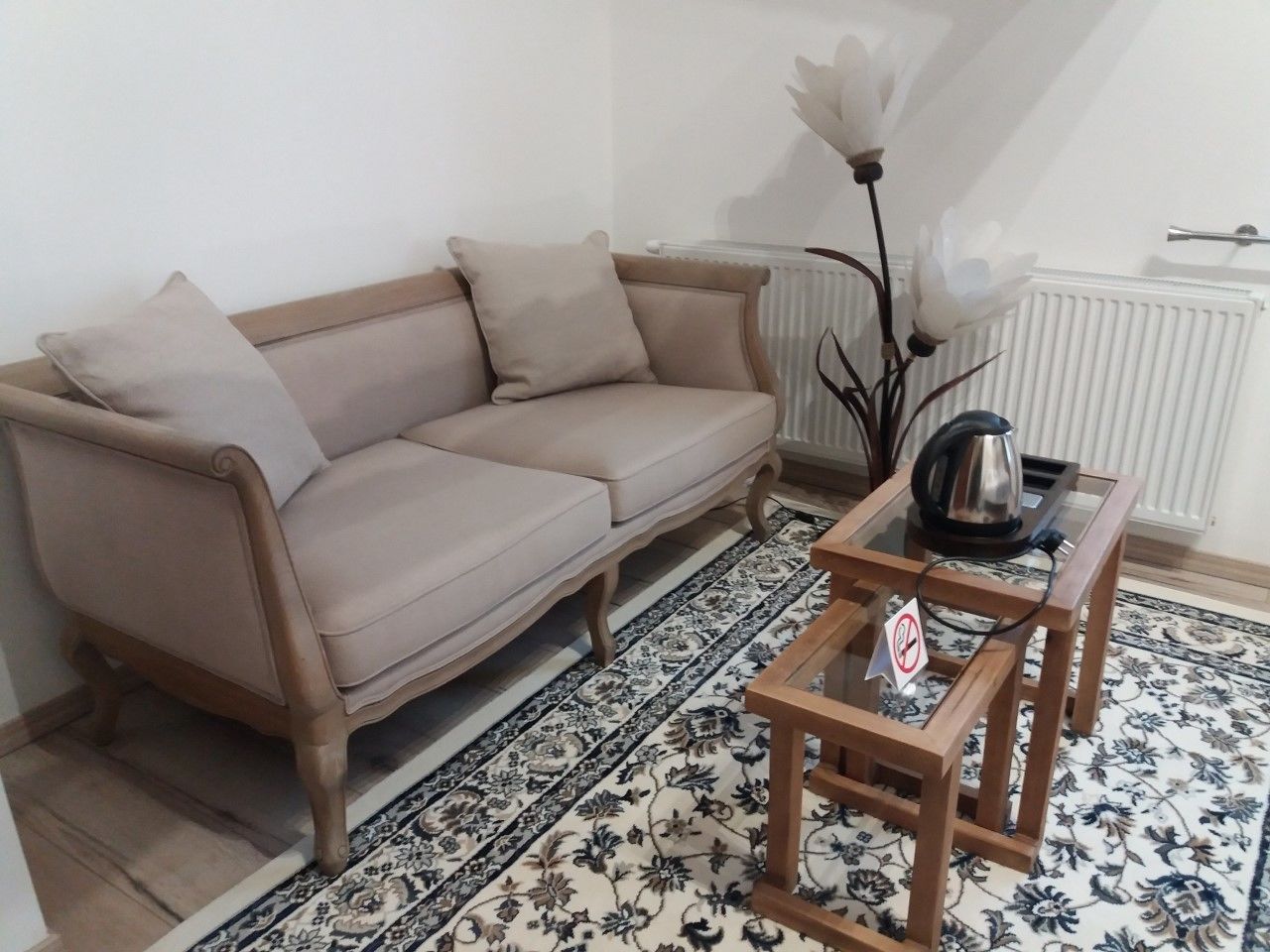 A living room with a beige sofa, a glass coffee table, and a patterned rug.