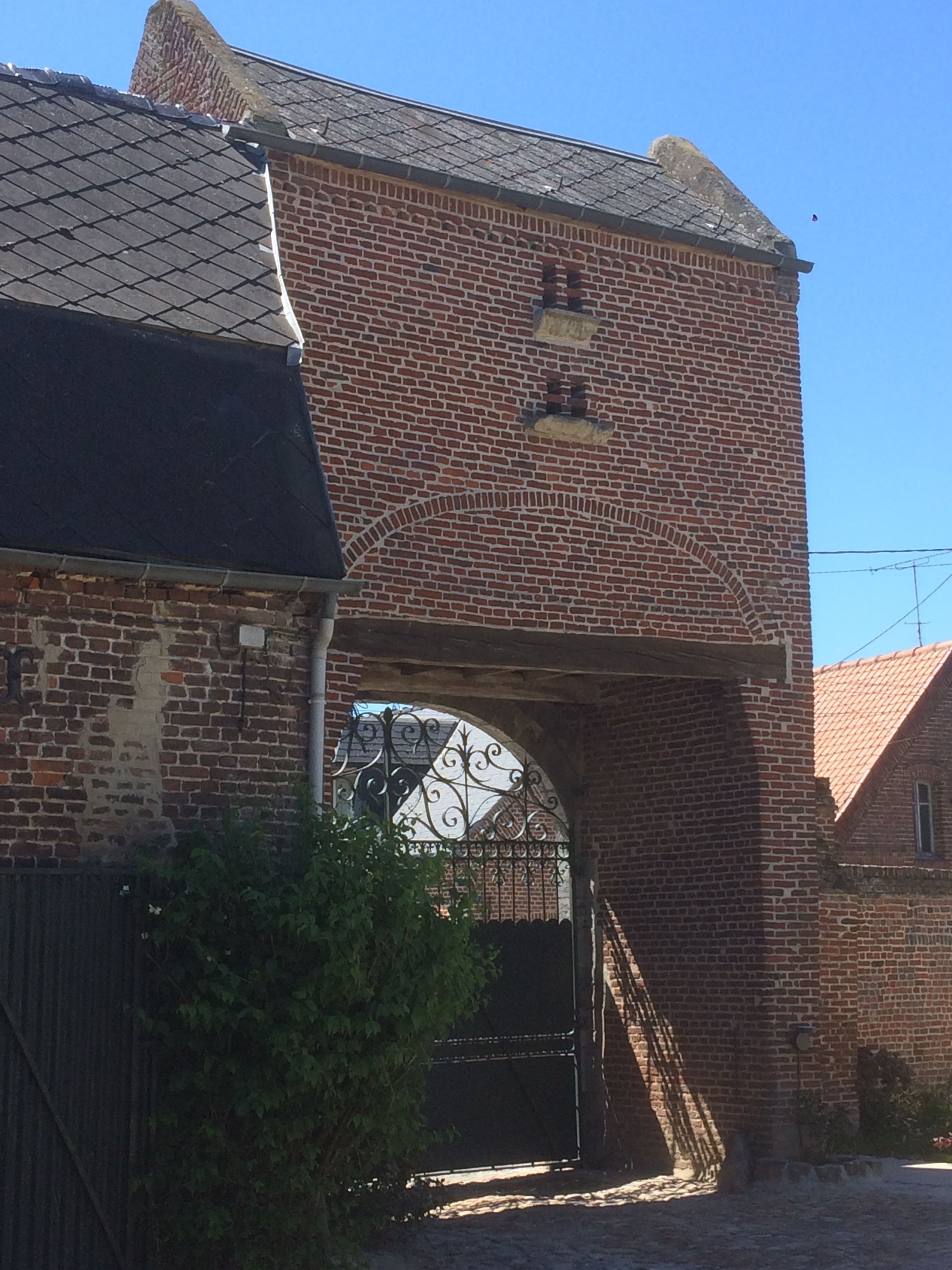 A brick building with a large arched entrance and a small tower-like structure on top.
