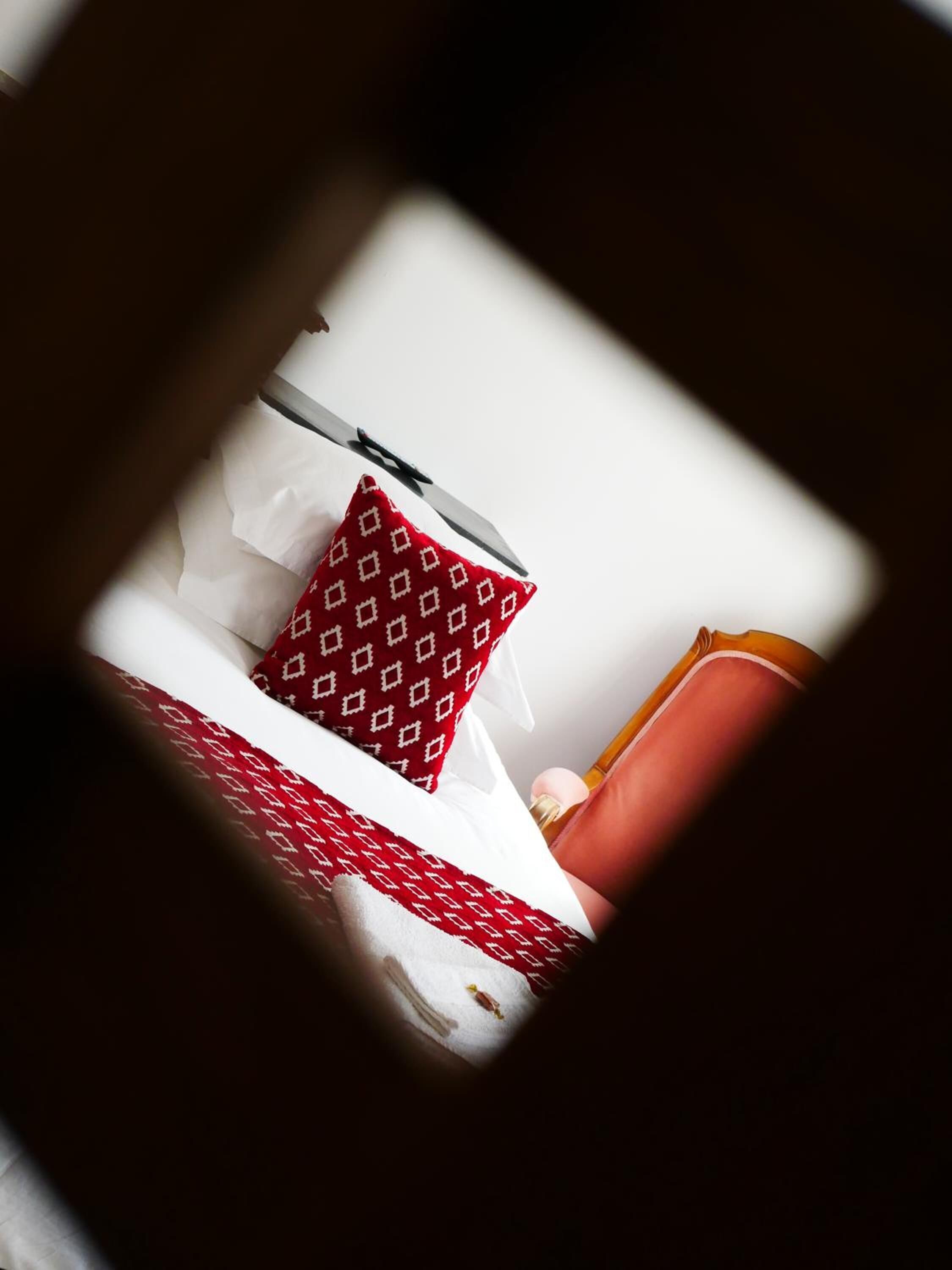 A bed with a patterned pillow and a red headboard.