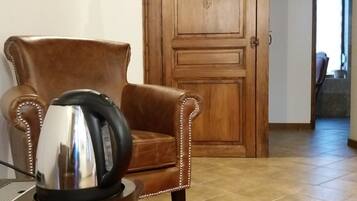 Una habitación con un sillón de cuero marrón, una mesa con un hervidor y una alfombra estampada.