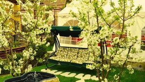 A garden with a stone fountain, stepping stones, and a bench under a tree. - Venesis House (Sighisoara)