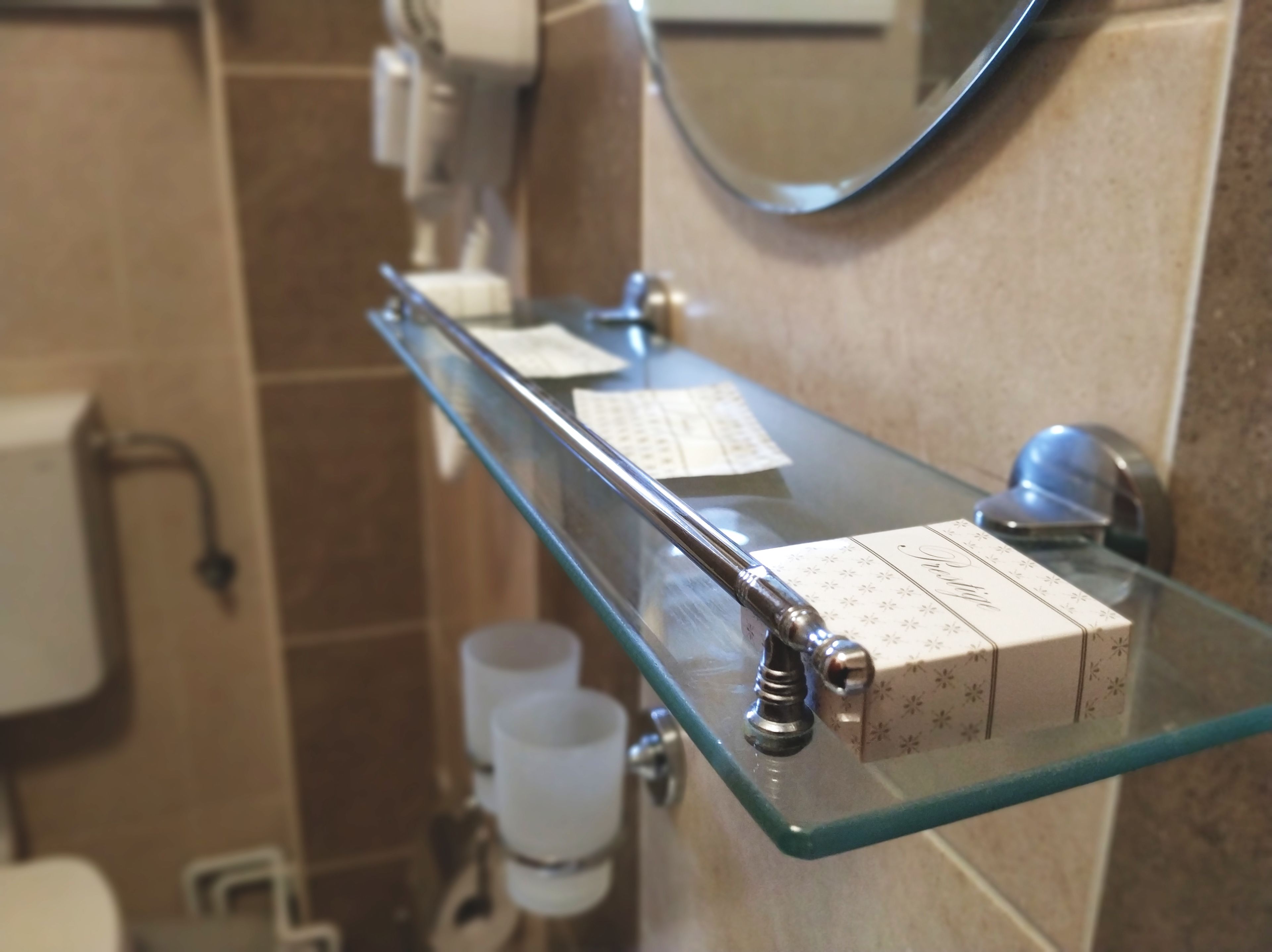 A glass shelf with toiletries and a mirror in a bathroom.