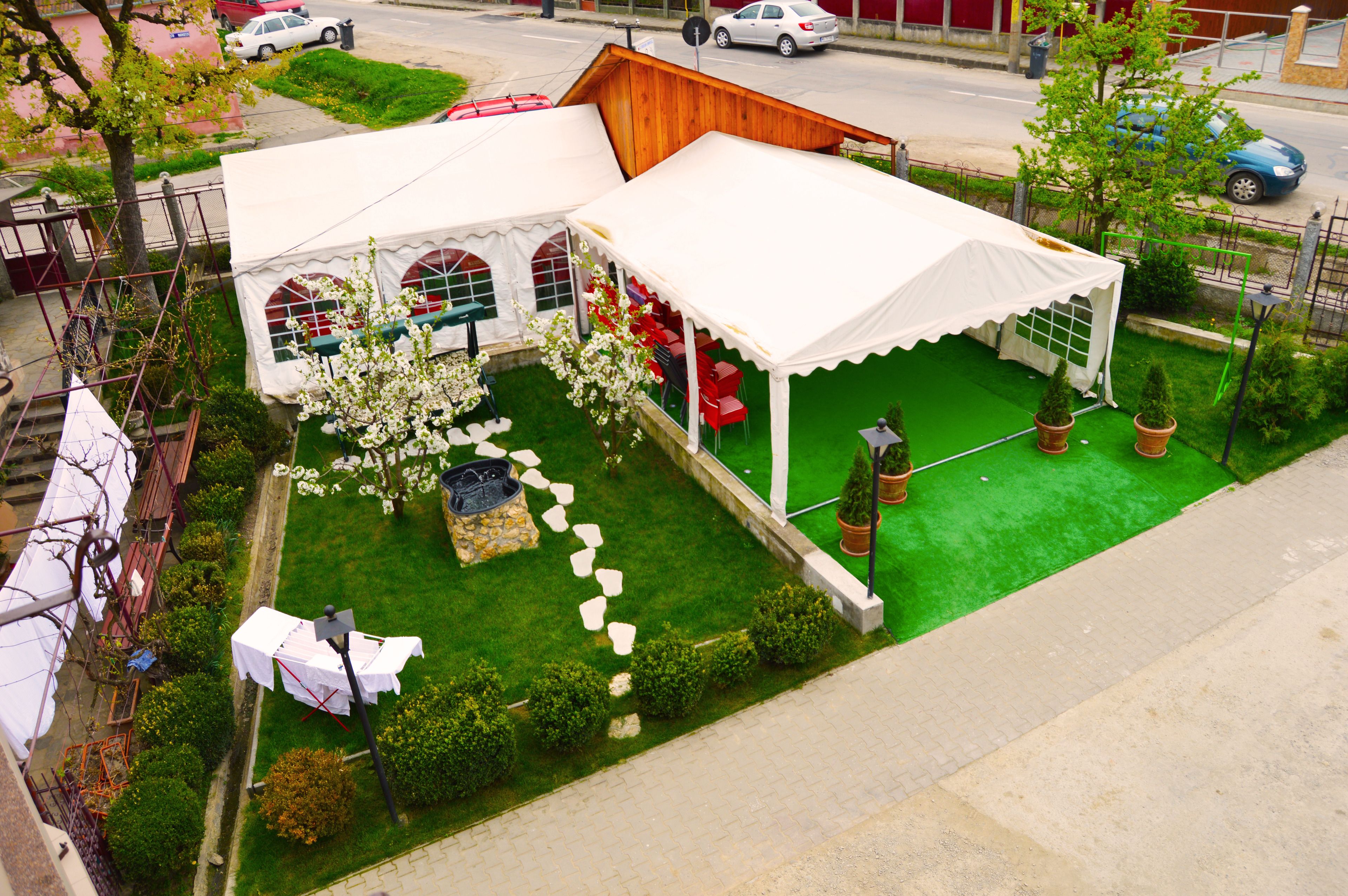 A white tent with a green lawn, stone pathway, and potted plants.
