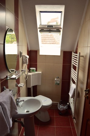 A compact bathroom with a toilet, sink, and a window above the toilet. - Venesis House (Sighisoara)