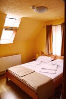 A room with a single bed, a window with curtains, a radiator, and a ceiling light fixture.